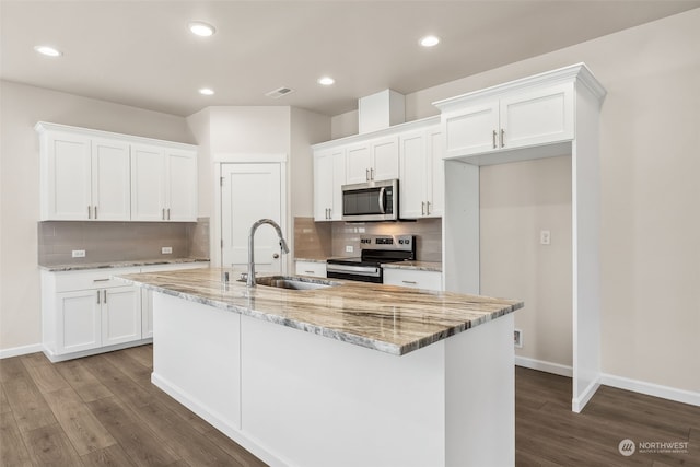 kitchen with stainless steel appliances, white cabinets, a center island with sink, and sink