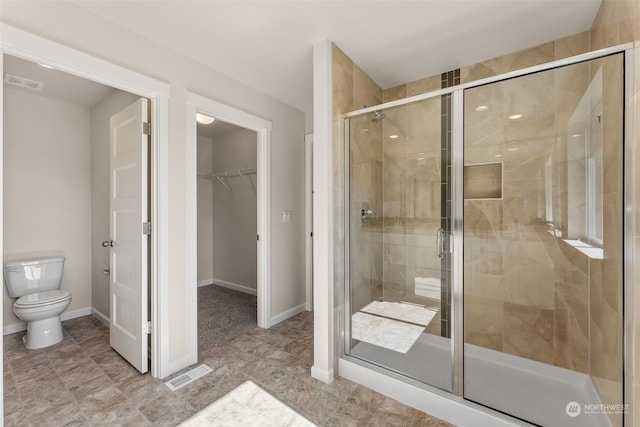 bathroom featuring toilet and a shower with shower door