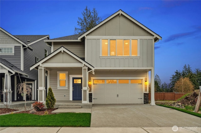 view of front facade featuring a garage, board and batten siding, driveway, and fence