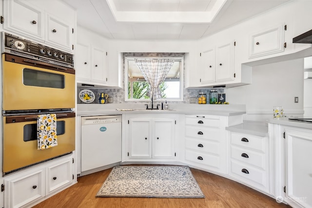 kitchen with white dishwasher, double oven, white cabinetry, and light hardwood / wood-style floors