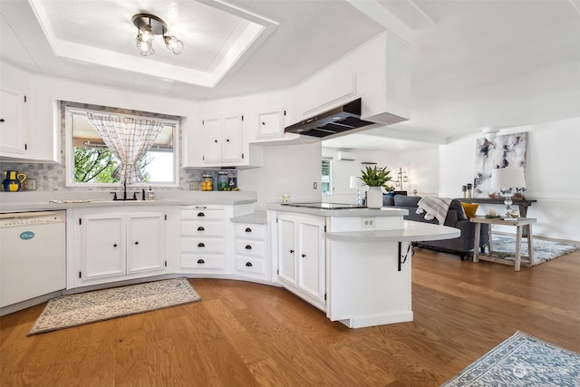 kitchen with light hardwood / wood-style flooring, a raised ceiling, dishwasher, kitchen peninsula, and white cabinets