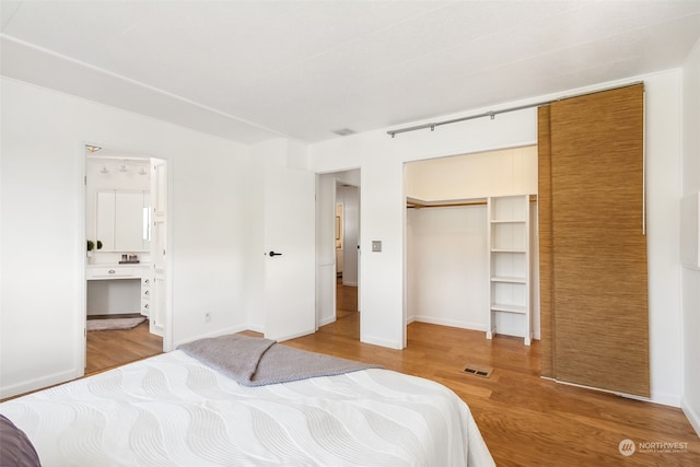 bedroom with wood-type flooring, a closet, and ensuite bathroom