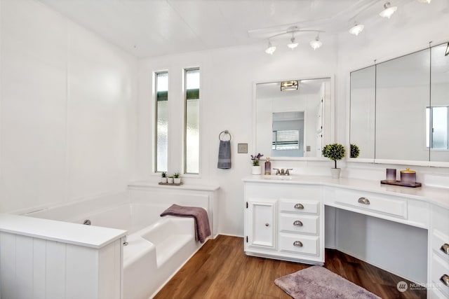 bathroom featuring hardwood / wood-style floors, a tub to relax in, and vanity