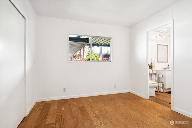 unfurnished bedroom featuring ensuite bath and hardwood / wood-style floors