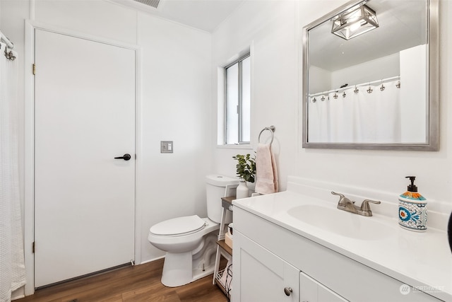 bathroom with toilet, vanity, and wood-type flooring