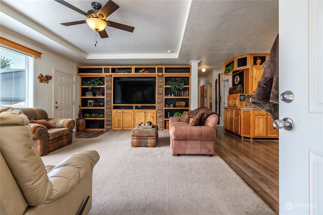 living room featuring ceiling fan, dark hardwood / wood-style flooring, and a tray ceiling