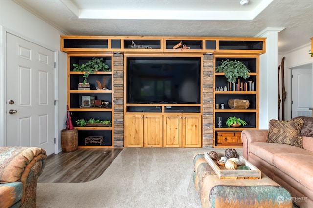 living room featuring hardwood / wood-style floors, built in features, ornamental molding, and a raised ceiling