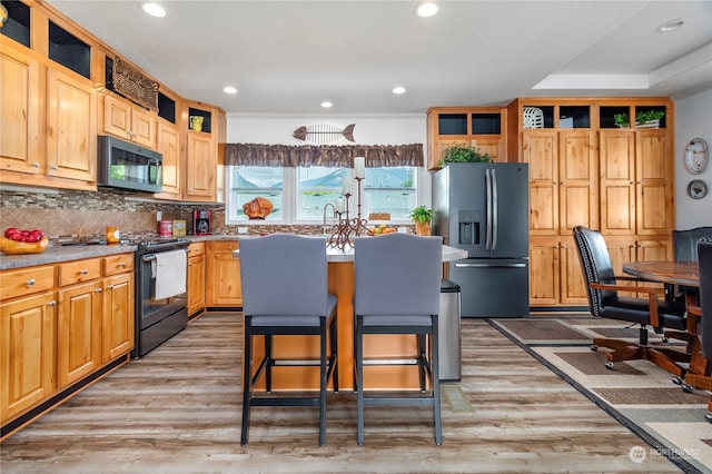 kitchen with light wood-type flooring, tasteful backsplash, a kitchen island, and stainless steel appliances