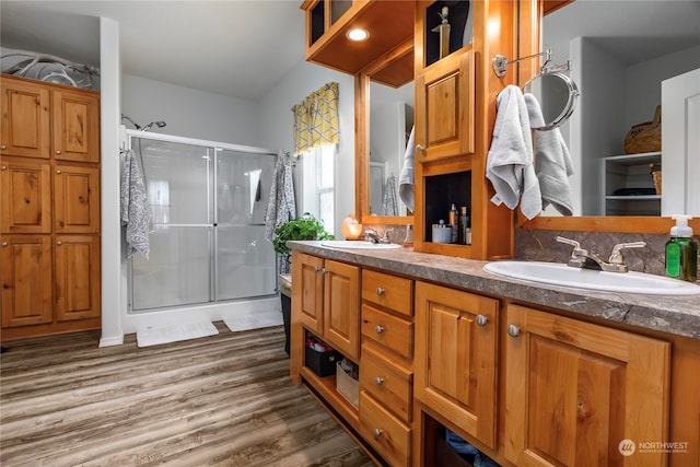 bathroom with dual vanity, a shower with door, and hardwood / wood-style flooring