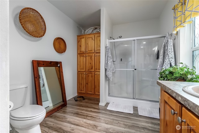 bathroom with walk in shower, vanity with extensive cabinet space, toilet, and hardwood / wood-style floors