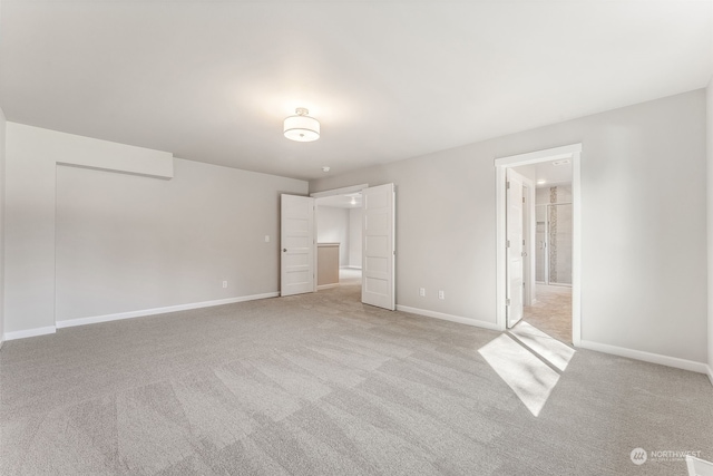 unfurnished bedroom featuring light carpet and ensuite bathroom