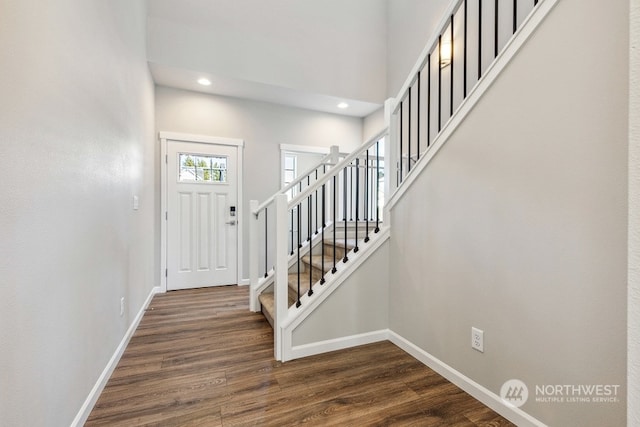 entrance foyer with dark wood-style floors, recessed lighting, a high ceiling, baseboards, and stairs