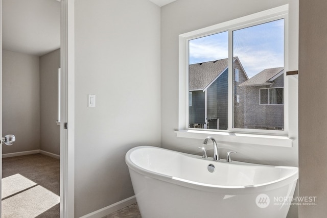 full bath featuring a freestanding tub and baseboards