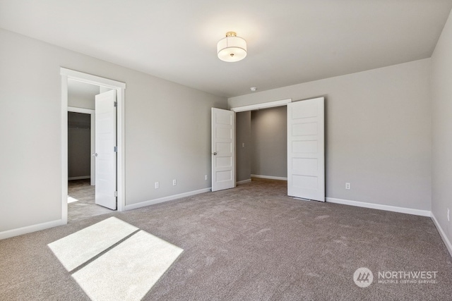 unfurnished bedroom with carpet, a walk in closet, and baseboards