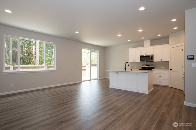 kitchen with dark wood-type flooring, sink, an island with sink, white cabinetry, and appliances with stainless steel finishes