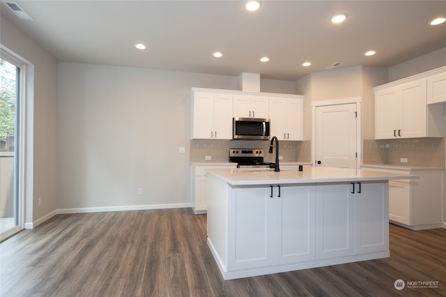 kitchen featuring white cabinets, an island with sink, appliances with stainless steel finishes, and hardwood / wood-style flooring