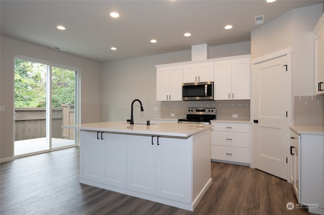 kitchen featuring dark hardwood / wood-style floors, a kitchen island with sink, white cabinets, decorative backsplash, and appliances with stainless steel finishes