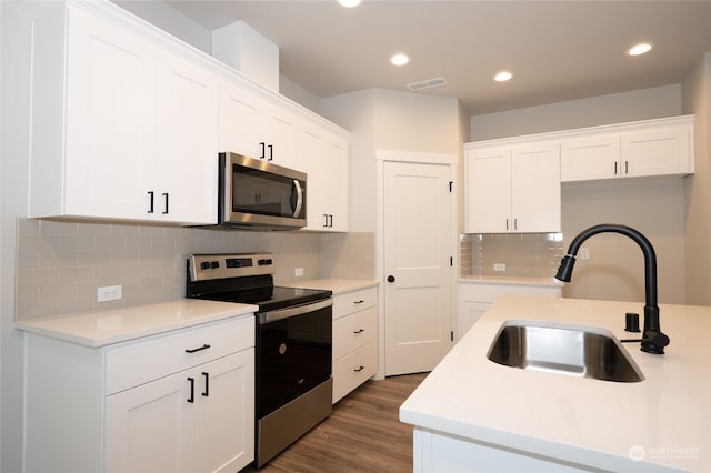 kitchen featuring sink, tasteful backsplash, white cabinetry, appliances with stainless steel finishes, and dark hardwood / wood-style flooring