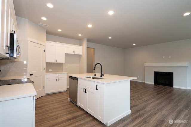 kitchen with dark wood-type flooring, sink, white cabinets, stainless steel appliances, and a center island with sink