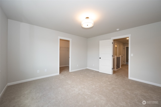 unfurnished bedroom with light carpet, a closet, and a walk in closet