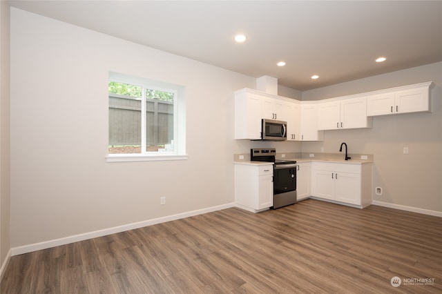 kitchen with appliances with stainless steel finishes, sink, dark wood-type flooring, and white cabinets