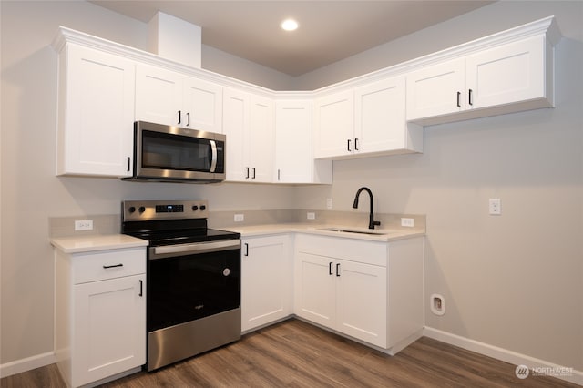 kitchen featuring stainless steel appliances, white cabinetry, dark wood-type flooring, and sink