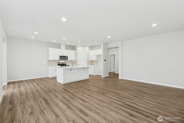 unfurnished living room featuring baseboards, recessed lighting, and light wood-style floors