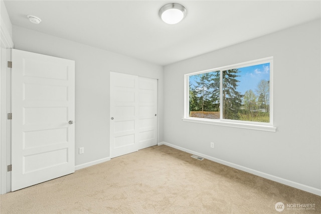 unfurnished bedroom with a closet, carpet, visible vents, and baseboards