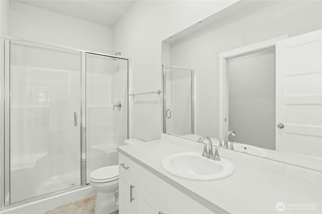 bathroom with a shower stall, toilet, and vanity