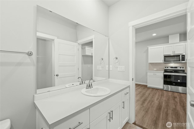 bathroom with toilet, vanity, and wood finished floors