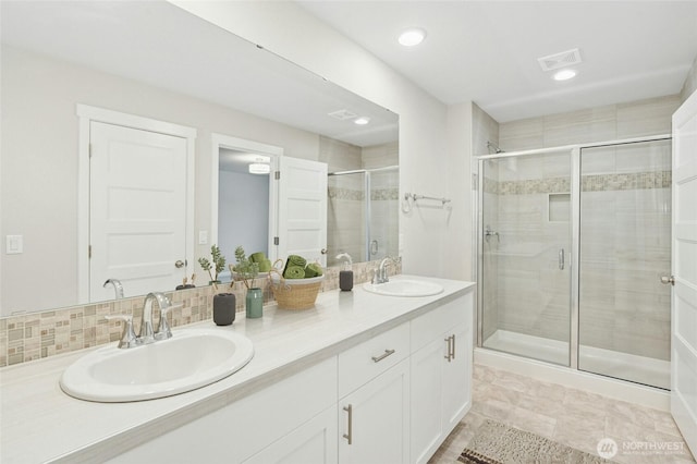 bathroom with visible vents, a sink, double vanity, and a stall shower