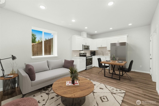 living room with light wood finished floors, baseboards, and recessed lighting