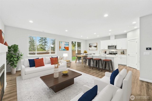 living room with recessed lighting, a wealth of natural light, light wood-style floors, and a fireplace