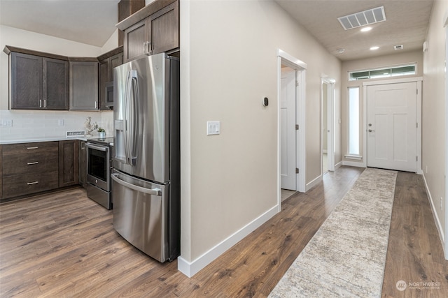 kitchen featuring dark brown cabinets, stainless steel appliances, hardwood / wood-style floors, and tasteful backsplash