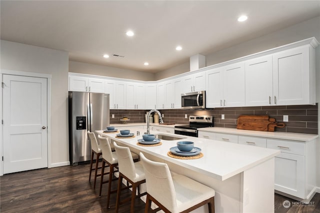 kitchen with sink, stainless steel appliances, white cabinets, and an island with sink