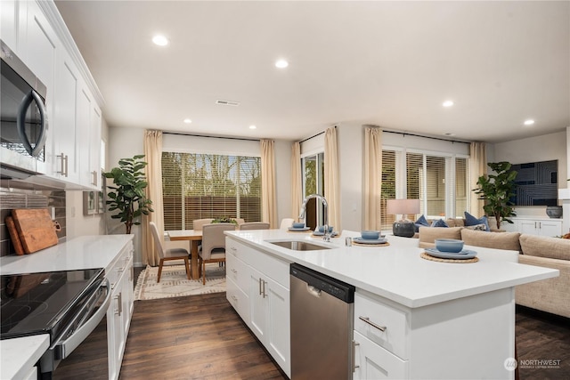 kitchen featuring appliances with stainless steel finishes, a kitchen island with sink, white cabinets, sink, and dark wood-type flooring