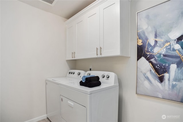 clothes washing area with washing machine and clothes dryer and cabinets