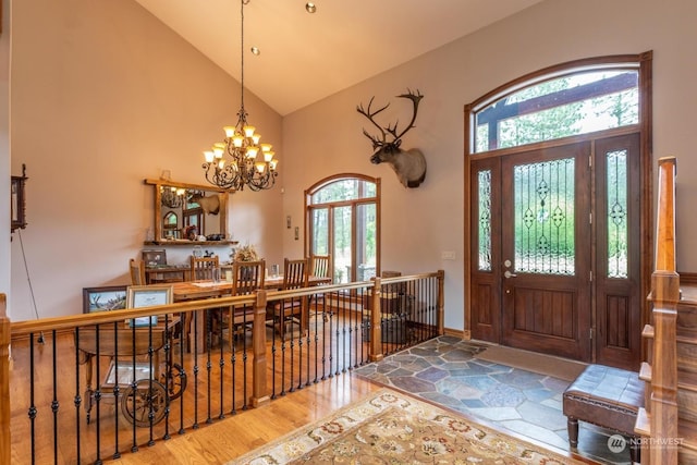 entryway with hardwood / wood-style flooring, a notable chandelier, a healthy amount of sunlight, and high vaulted ceiling