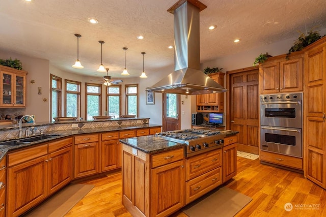 kitchen featuring sink, light hardwood / wood-style flooring, decorative light fixtures, island exhaust hood, and stainless steel appliances