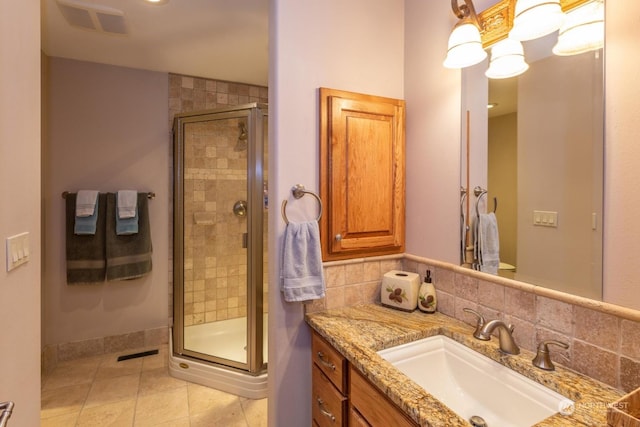 bathroom with tile patterned flooring, vanity, an enclosed shower, and backsplash