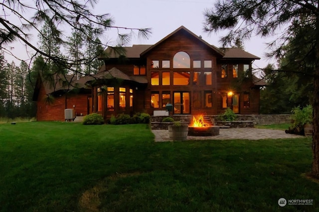 back house at dusk featuring a yard, a patio, an outdoor fire pit, and central air condition unit