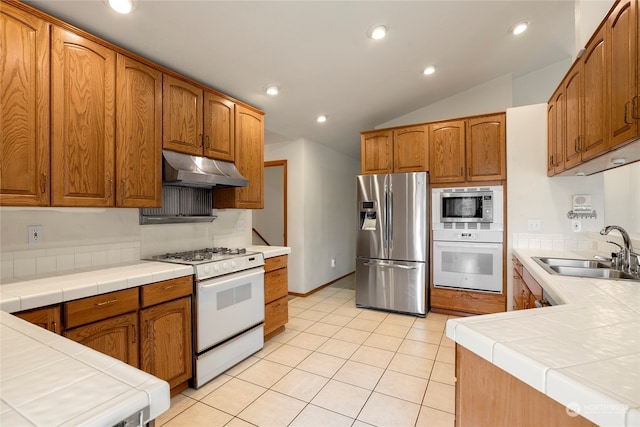 kitchen featuring tile countertops, stainless steel appliances, recessed lighting, a sink, and under cabinet range hood