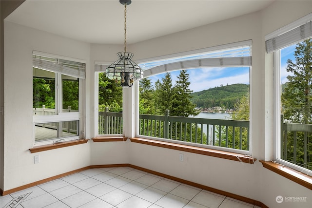 unfurnished sunroom featuring a water view and an inviting chandelier