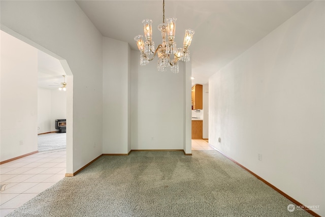 spare room with arched walkways, light tile patterned flooring, light carpet, a ceiling fan, and baseboards