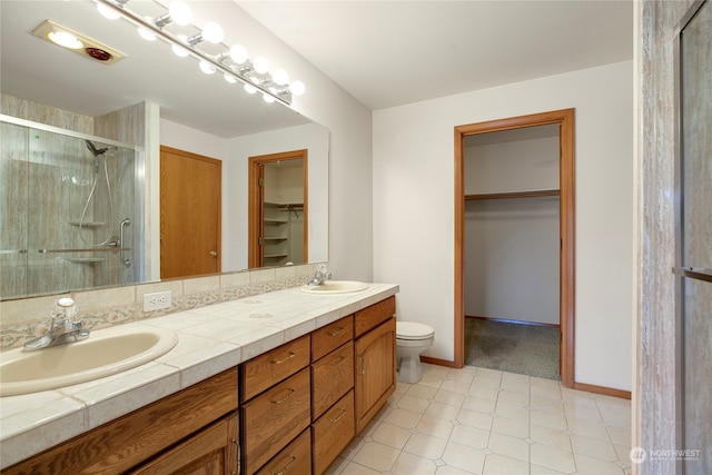 bathroom with a sink, a shower stall, toilet, and double vanity