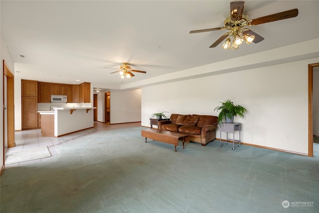 living area featuring light carpet, a ceiling fan, and baseboards