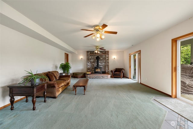 interior space featuring a wood stove, baseboards, carpet floors, and a ceiling fan