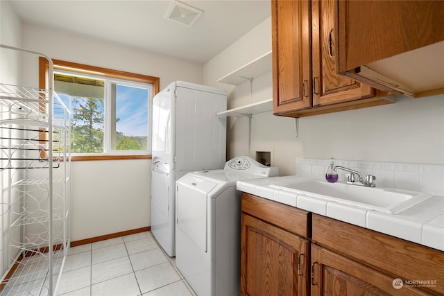 washroom with washer / clothes dryer, cabinet space, light tile patterned flooring, a sink, and baseboards