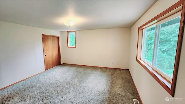 unfurnished room featuring carpet floors, visible vents, and baseboards