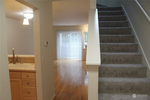 stairway featuring sink and hardwood / wood-style flooring